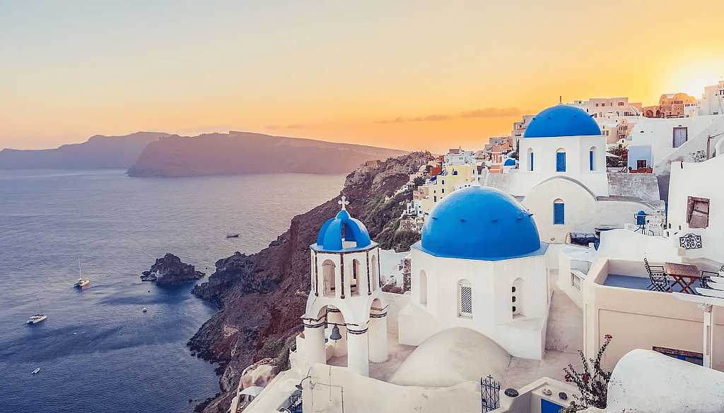 A sunset view of the iconic whitewashed buildings and the open sea in Santorini, Greece.