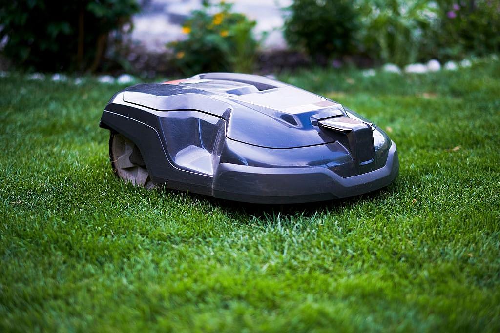 A robotic mower cutting lawn grass in a backyard.