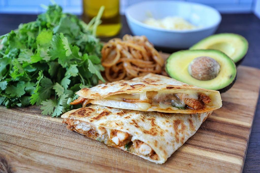 A plate of Chicken Shawarma Quesadiilas with avocados and caramelized onions.