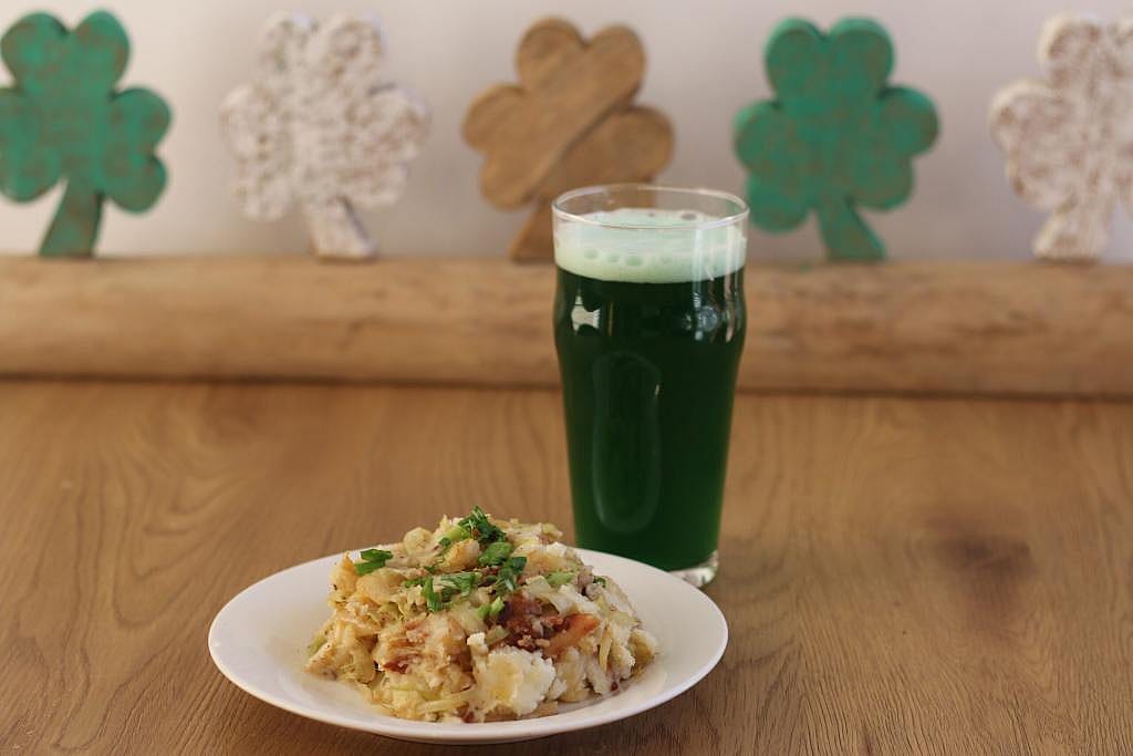 A plate of Loaded Grilled Colcannon with a glass of green soda.