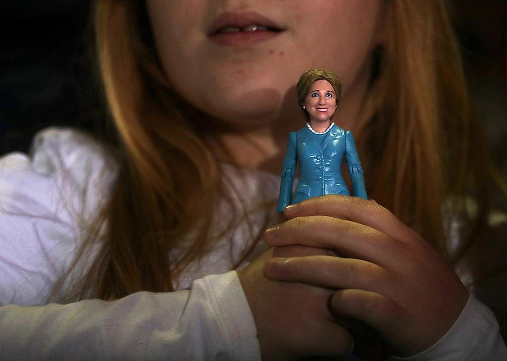 A young girl holding a doll of 2016 Democratic presidential nominee and former Secretary of State, Hillary Clinton.