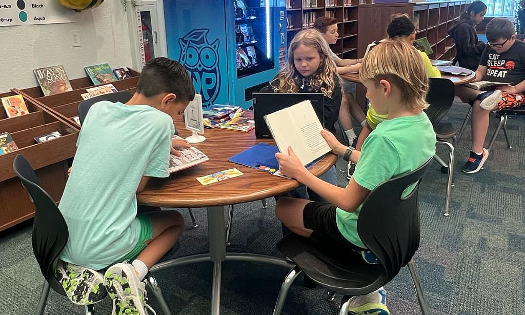 Third grade students Brady Jackson, Everly Collier and Finn Fratila read books in the Windsor Park Elementary library.