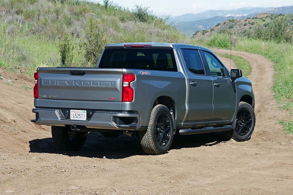 Rear view of silver 2026 Chevrolet Silverado 1500 parked on dirt road.