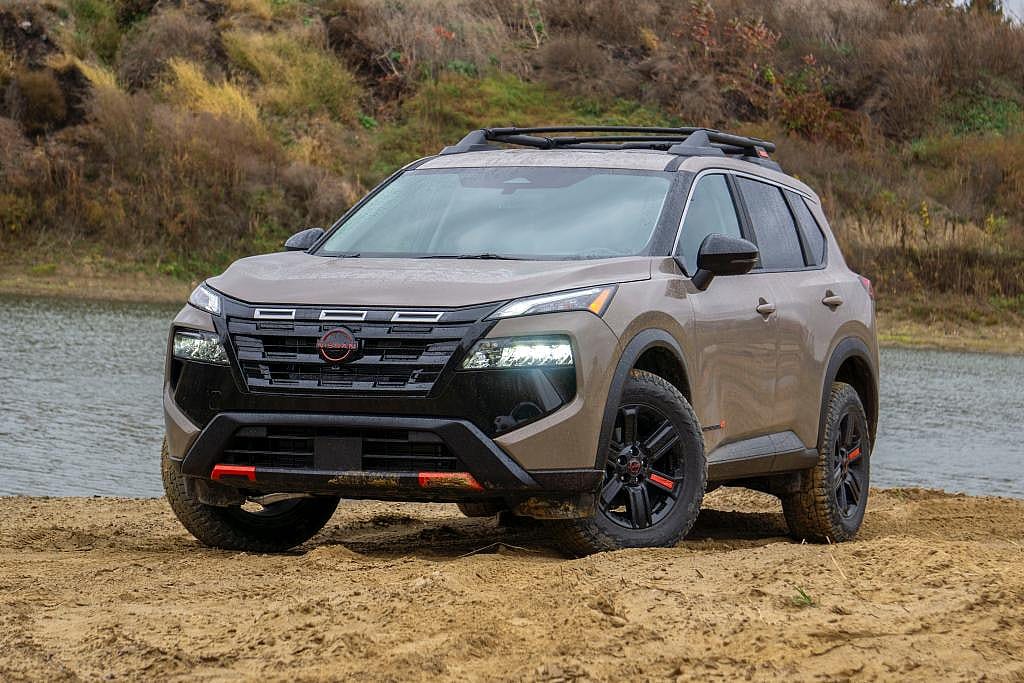 Front low-angle view of a light brown 2025 Nissan Rogue parked on the sandy banks of a river.