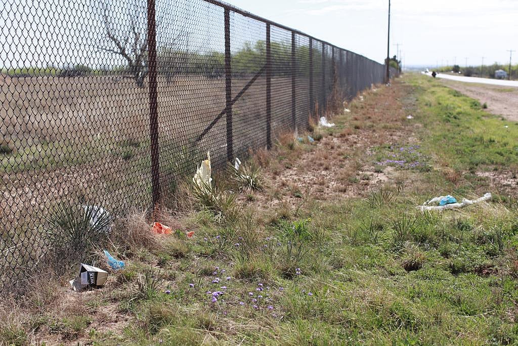 Six packs, boot covers and other construction debris litter the fenceline on the road leading to the data center.