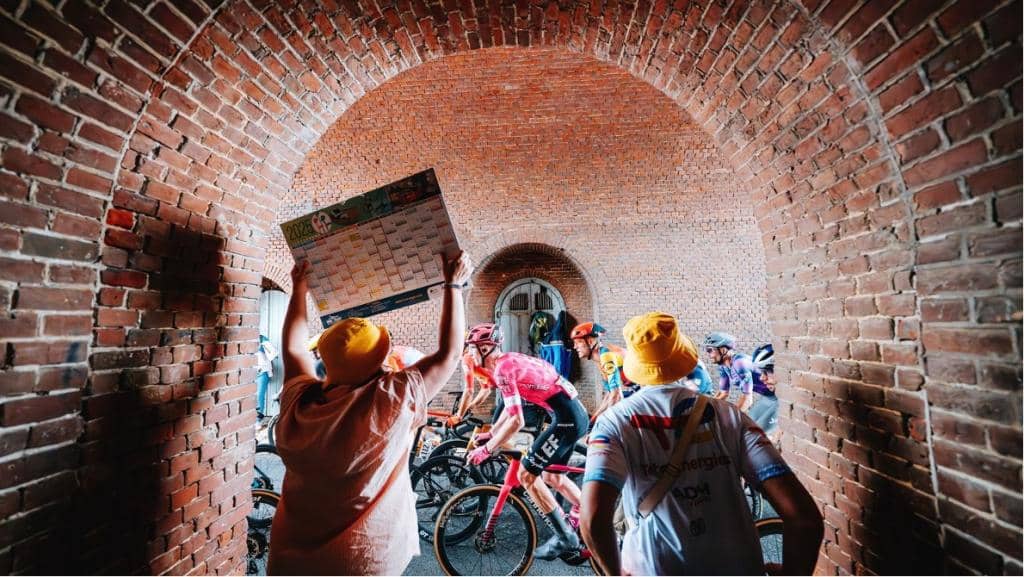 Cyclists navigating through a brick tunnel during the Tour de France. 