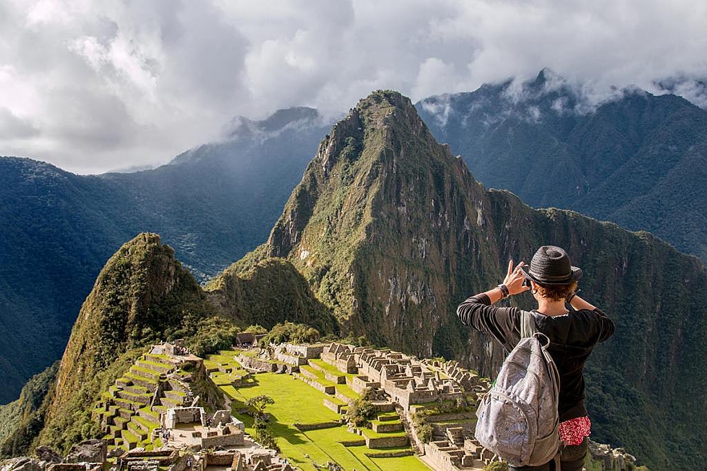 A tourist taking a panoramic view of Machu Picchu, located in the Andes mountains of Peru.