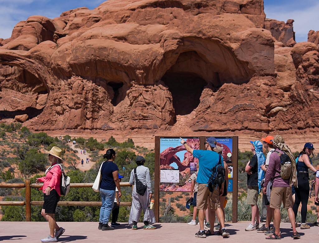 Tourists look at information about Double Arch Trail inside Arches National Park near Moab on Thursday, April 9, 2026.