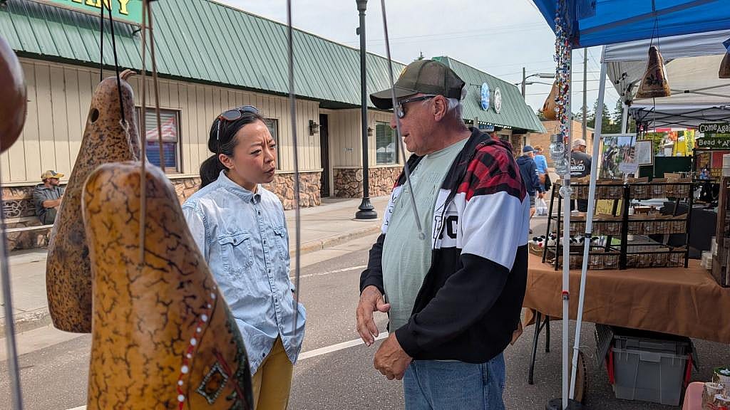 Hong speaks to Bob Boesch next to the thunder gourds they sell.