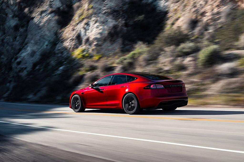 Red 2023 Tesla Model 3 rear three-quarter view on the road.