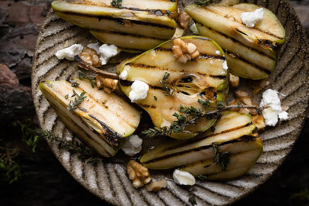A plate of grilled pear halves with cheese.