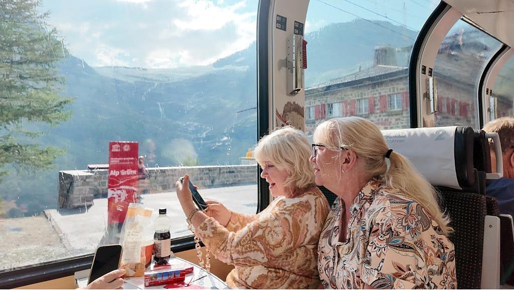 Tourists enjoying their vacation inside a modern train journeying through the European Alps mountains.