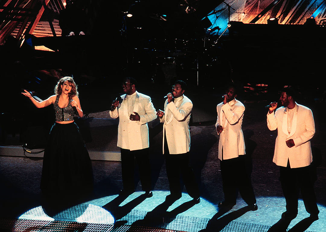 Mariah Carey performing with Boys II Men onstage.