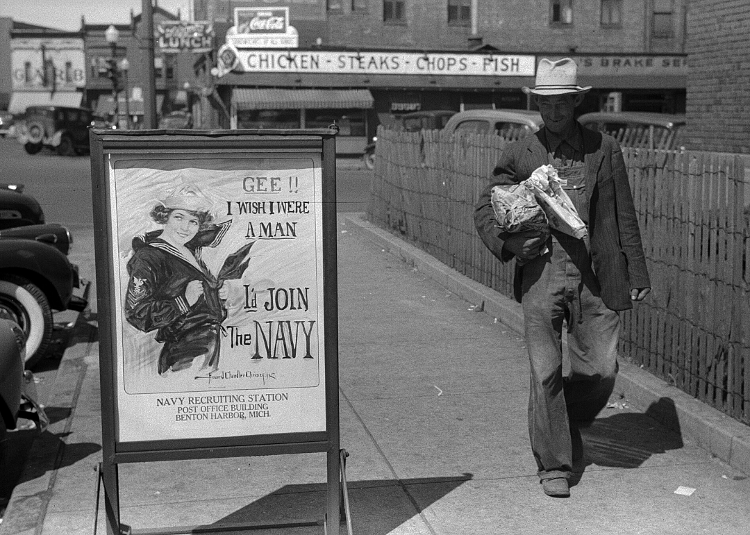 Migrant worker passes sign advertising Navy recruitment 