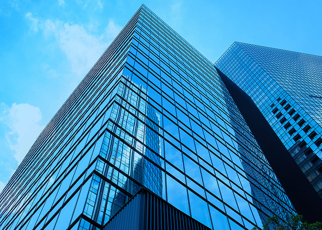 Large corporate office buildings reflecting blue sky.