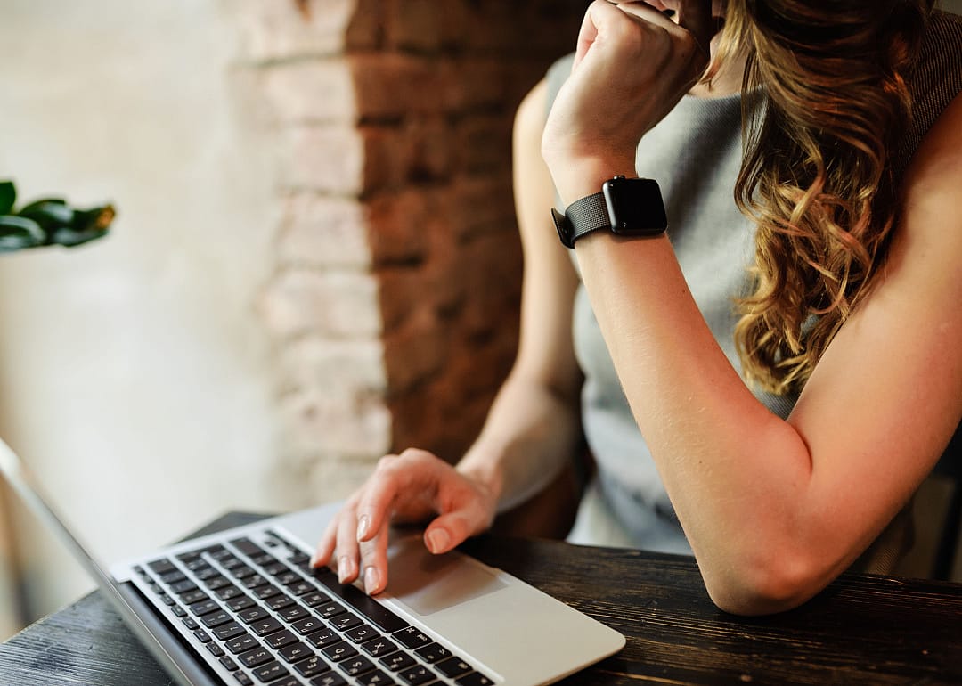 Person wearing smartwatch using laptop computer.