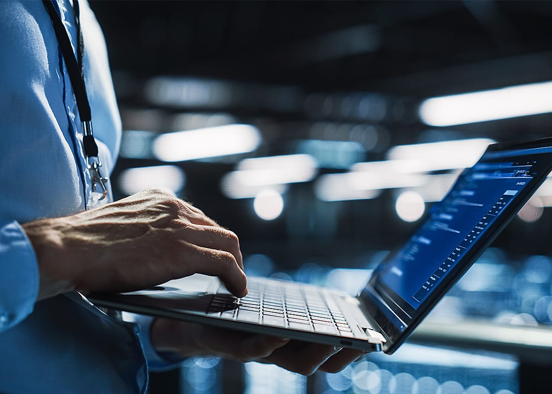 Person with laptop and security badge in digital monitoring room.