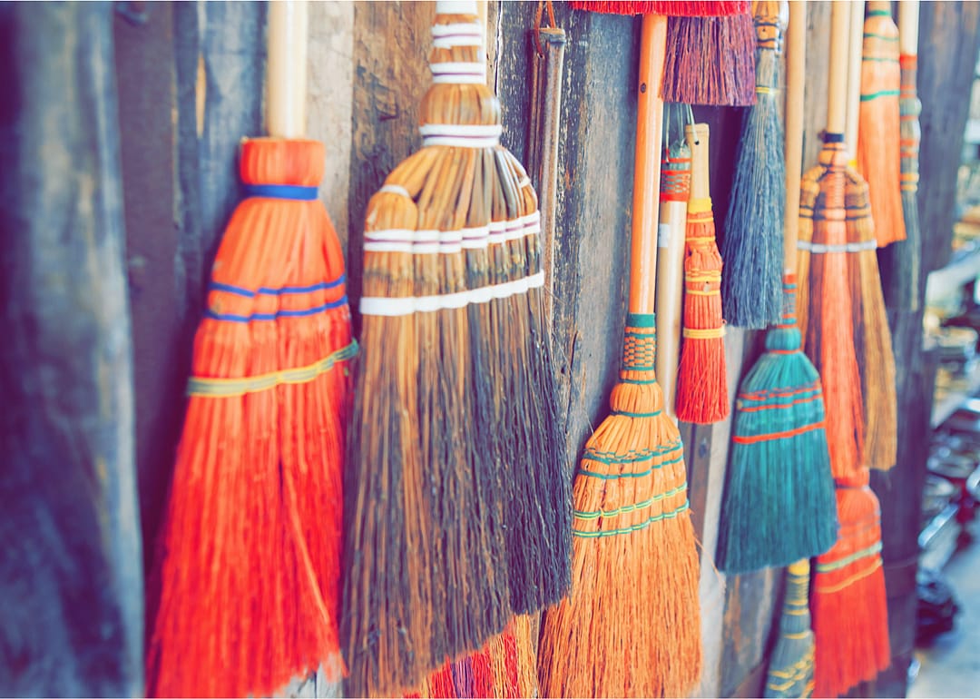 A collection of colorful brooms hanging on a wooden wall.