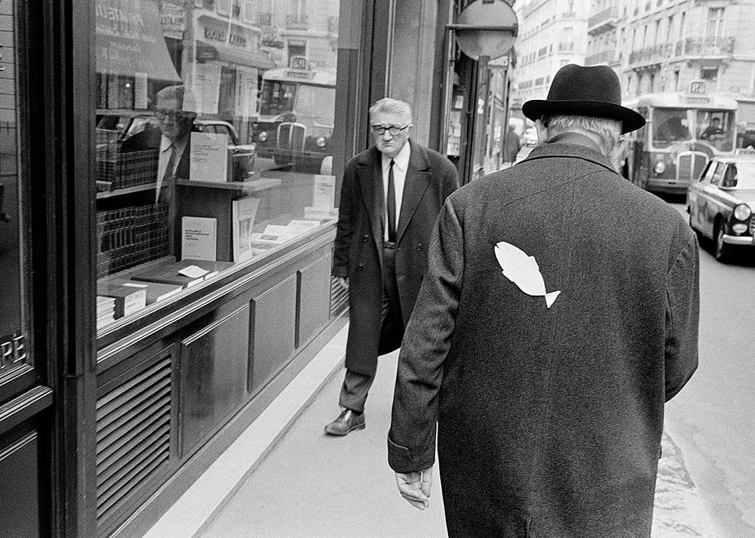 Man walking with a paper fish on his back.