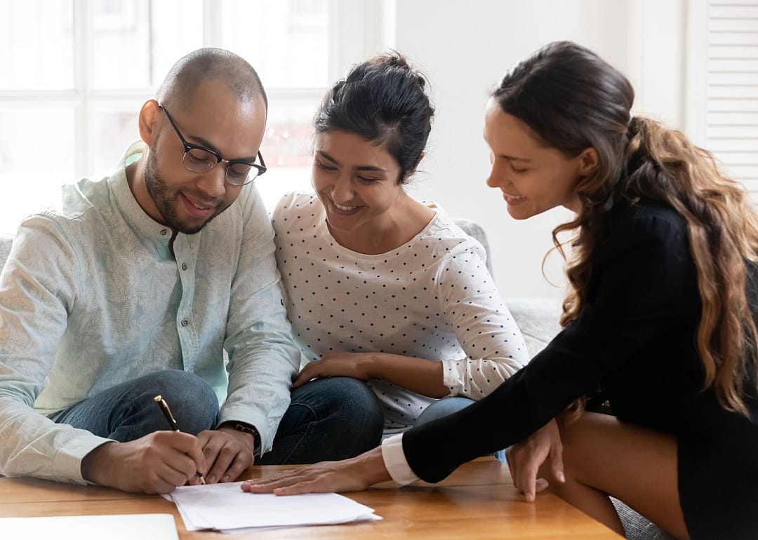 Real estate agent with couple signing contracts.