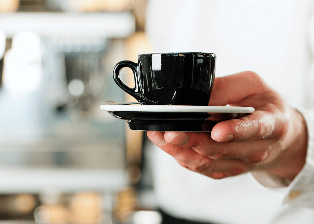 Close-up barista presenting espresso drink.