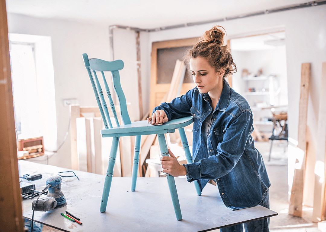 Person in workshop sanding vintage chair.