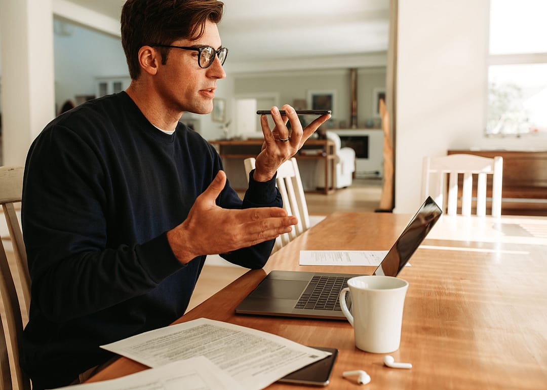 Man talking on speakerphone working from home.