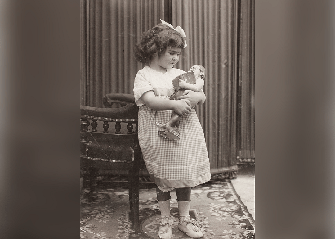 Young Frida Kahlo holding a doll.