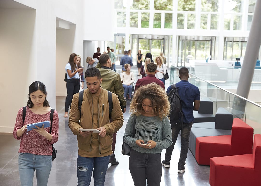 Students walk in university campus with phones