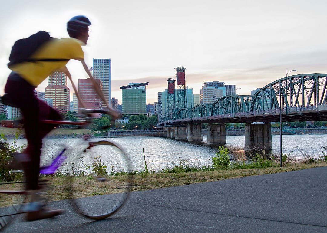 Person riding a bicycle along river in Portland