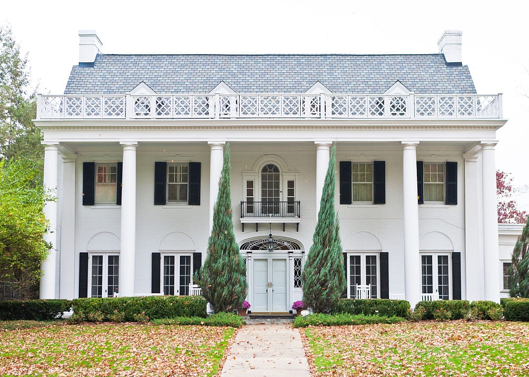 Exterior Neoclassical mansion with white columns and black shutters.