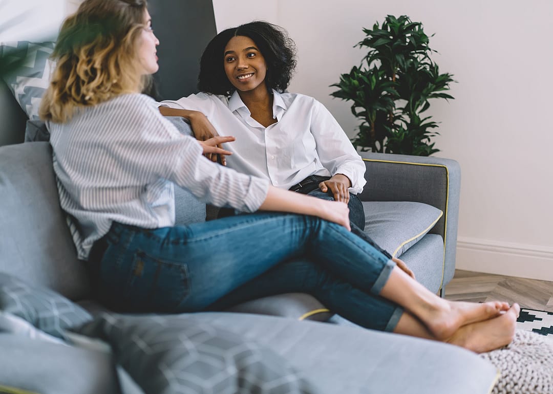 Two friends sitting on living room couch.