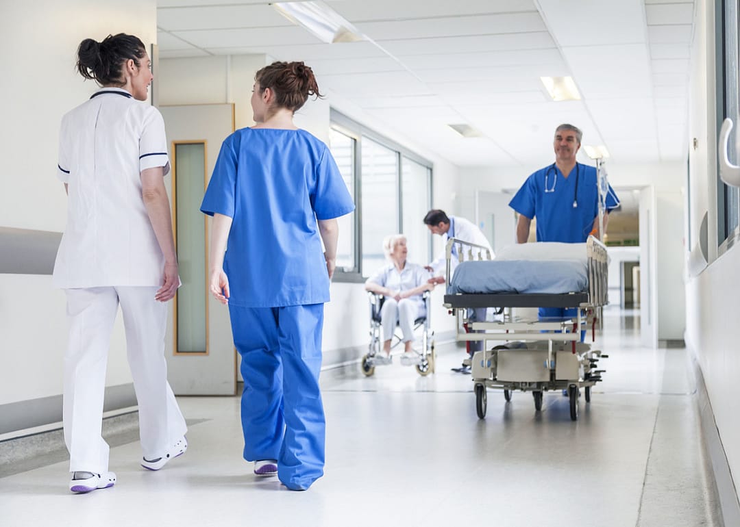 Nurse pushing gurney in hospital corridor.