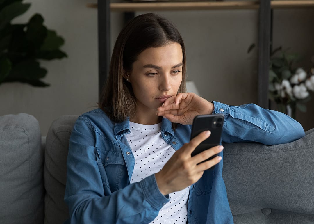 Person looking at phone on sofa.