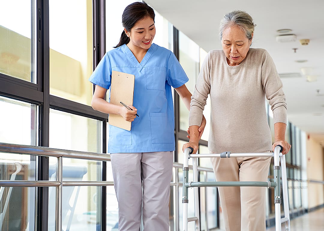 Therapist works with woman using walker.