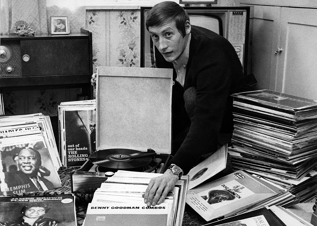 Man displaying jazz record collection at home.