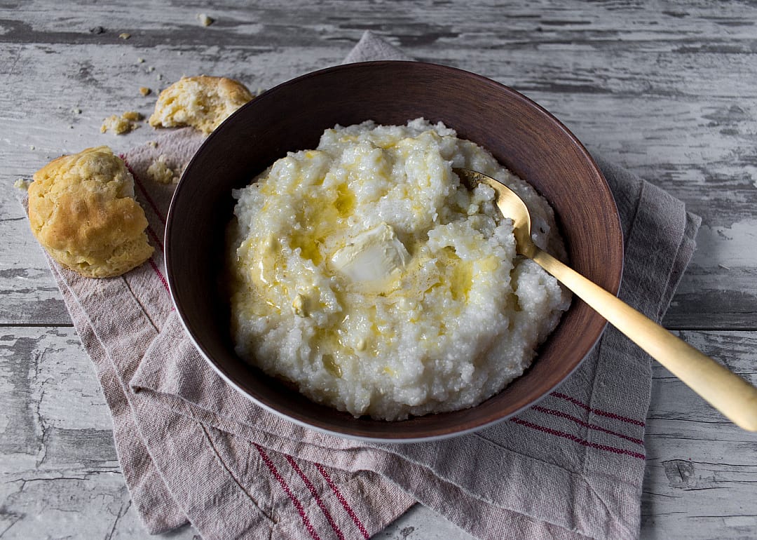 Buttered grits with biscuits on wood table.