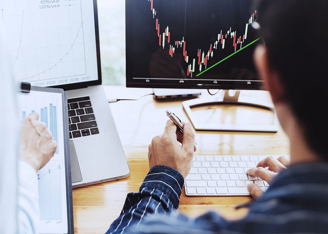 Person looking at financial chart on monitor.