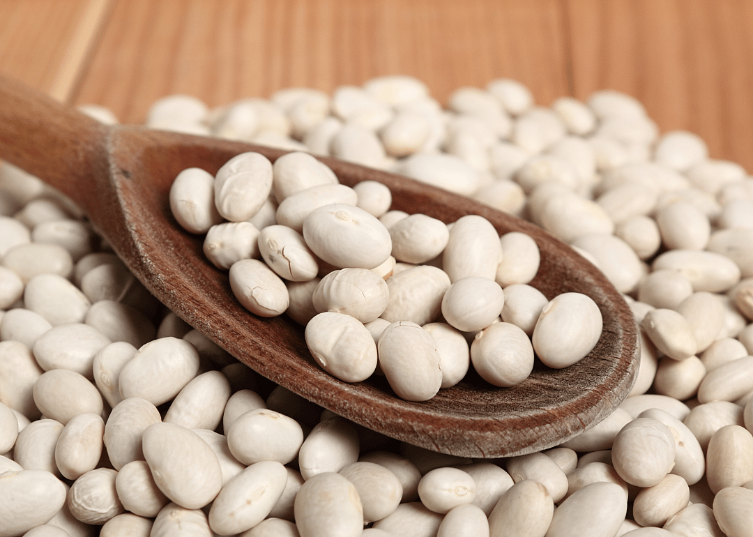 Navy beans in wooden spoon.