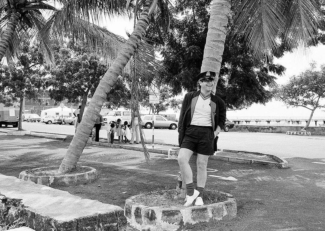 Elton John standing under a palm tree on Montserrat.