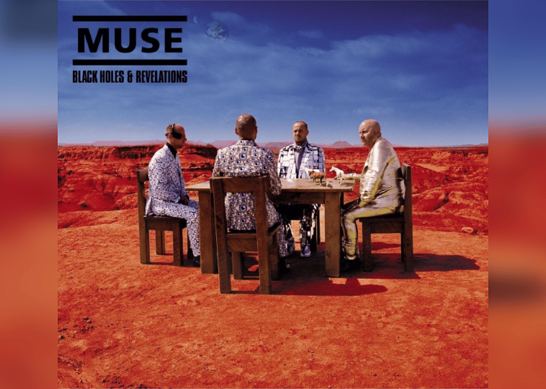 The album cover shows men in suits at a wooden table in a desert with a canyon in the background.
