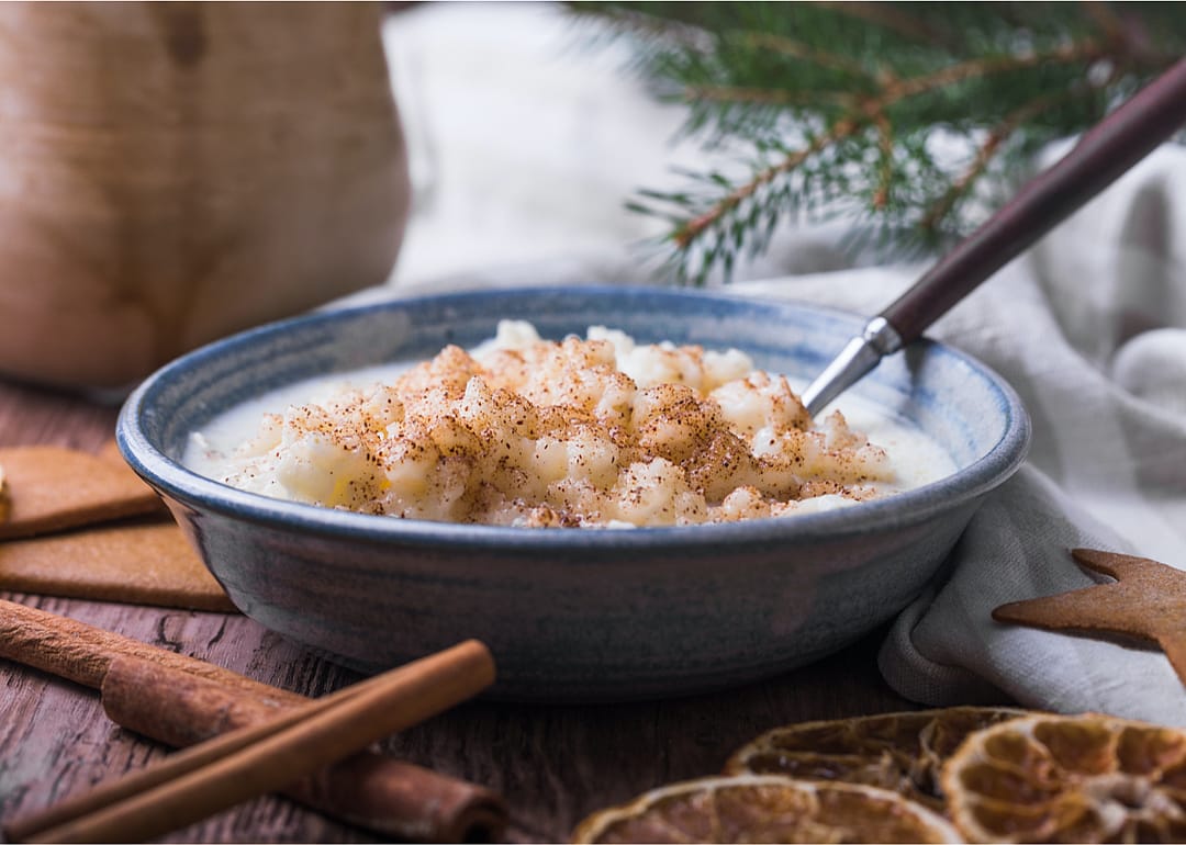 A bowl of rice pudding with a Christmas tree branch in the background.