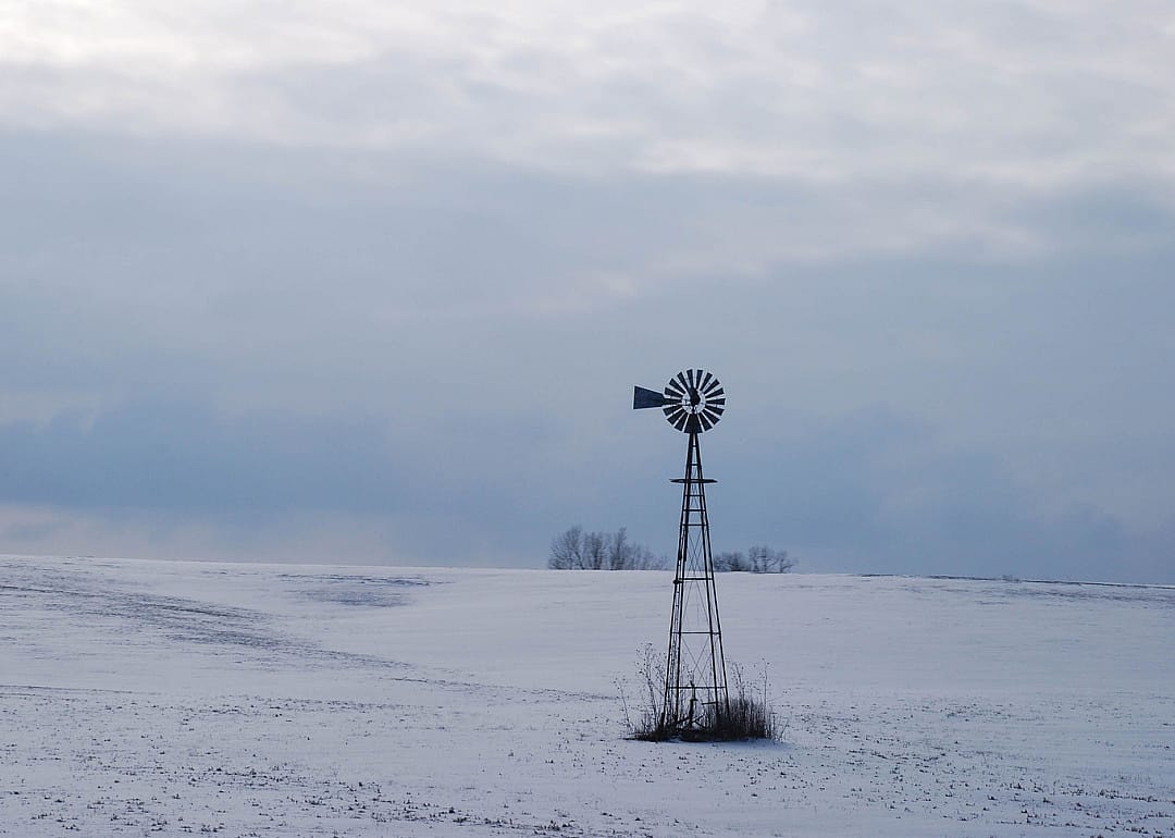 A windmill in a snowy winter landscape.