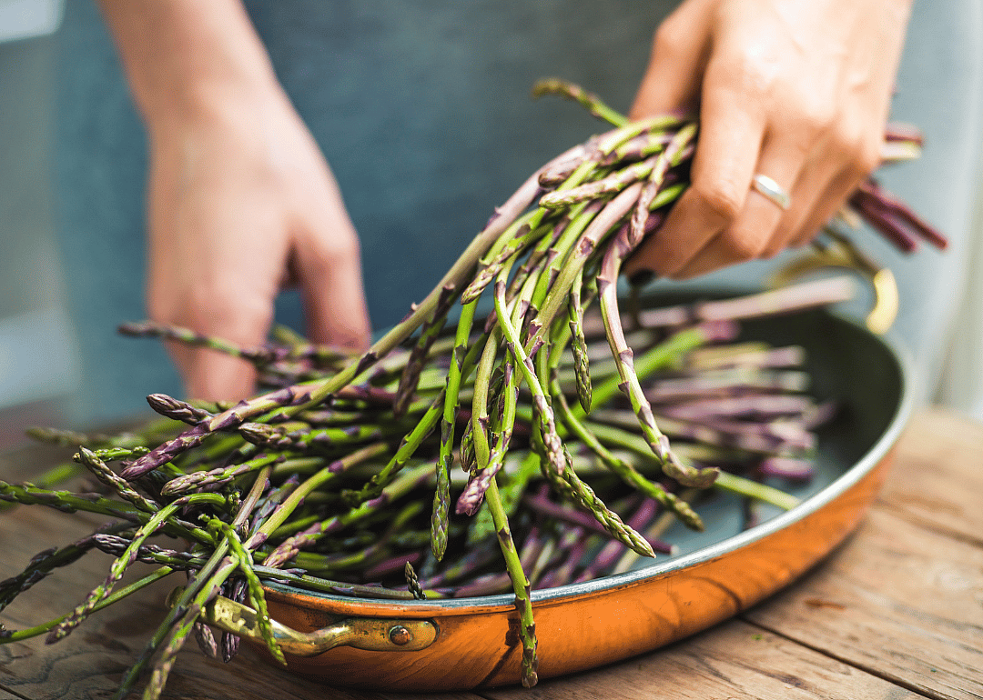Person preparing fresh asparagus.