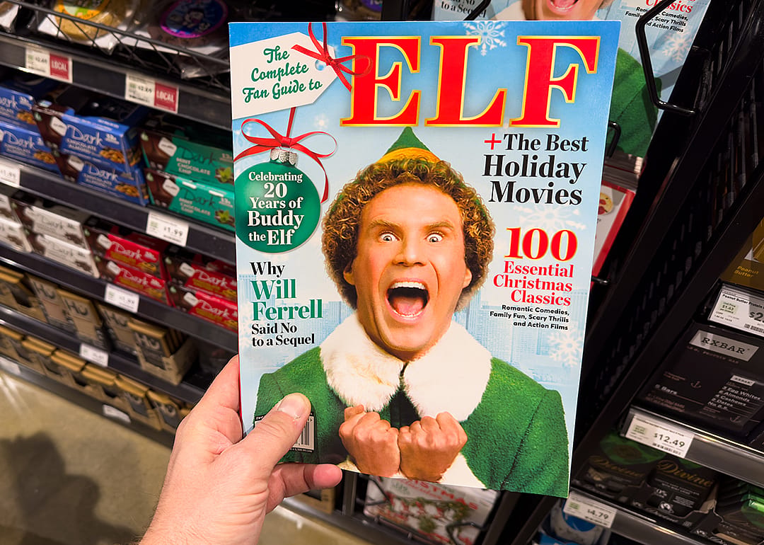 Hand holding a book titled The Complete Fan Guide to Elf with a photo of Will Ferrell.