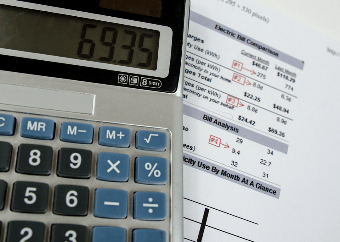 A calculator atop a pile of household utility bills