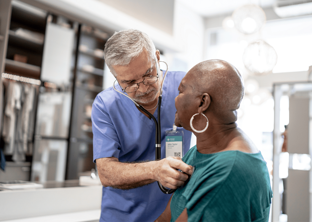 A doctor tends to an older patient.