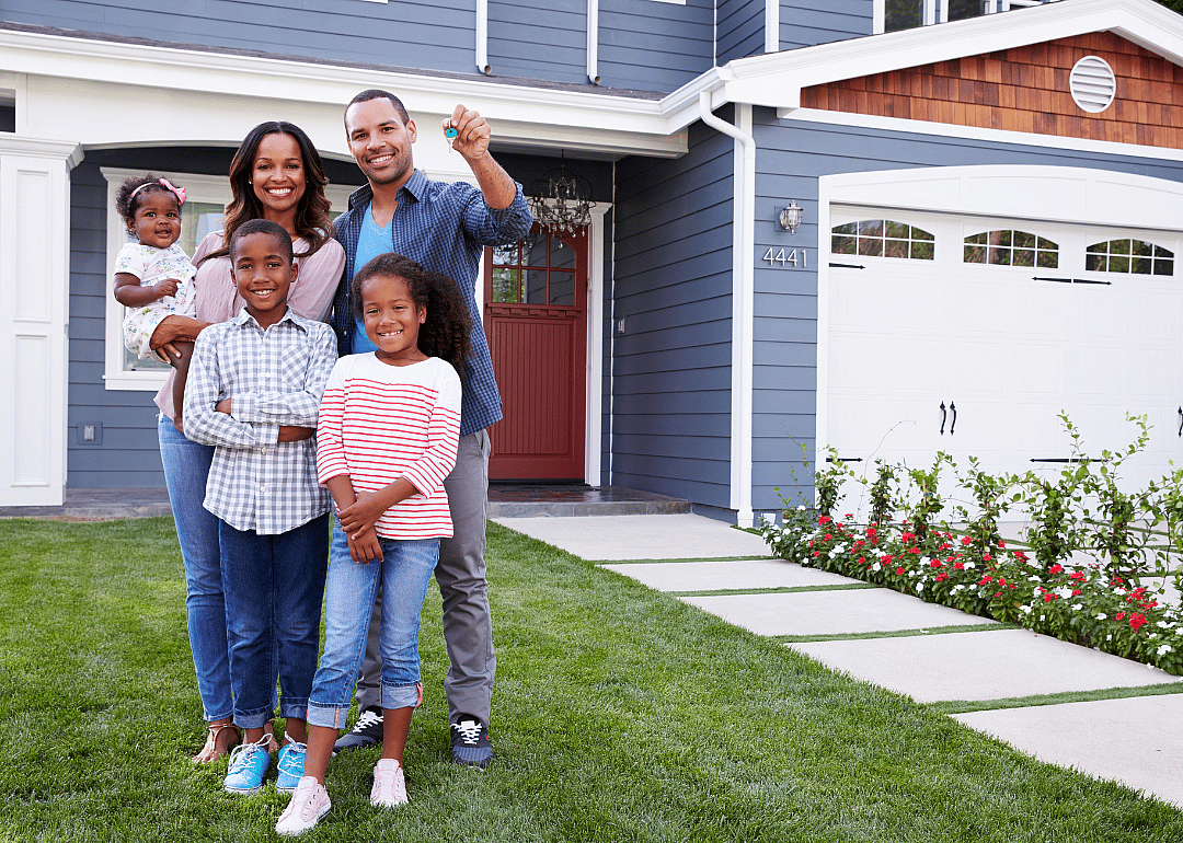Parents, son, and daughter stand in front of a new home.