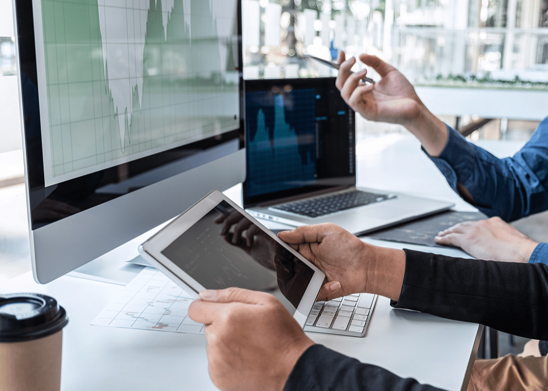 Two sets of hands operate a laptop, a monitor and a tablet.