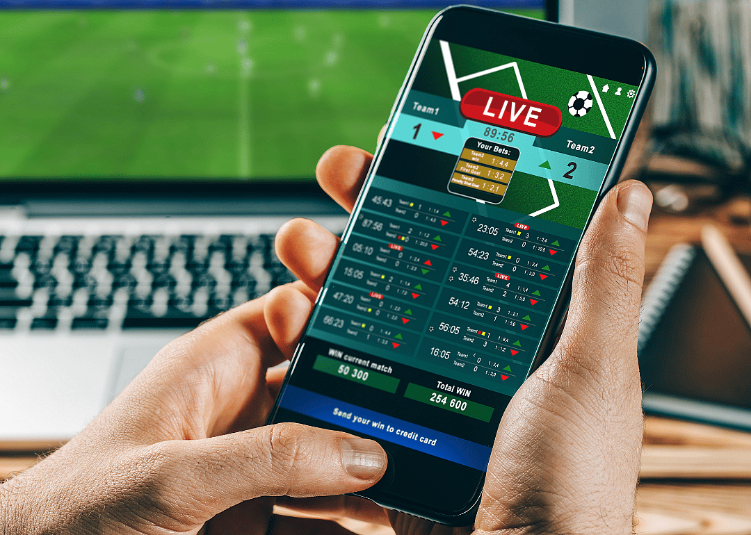 Closeup of a person holding a mobile phone looking at online sports betting.